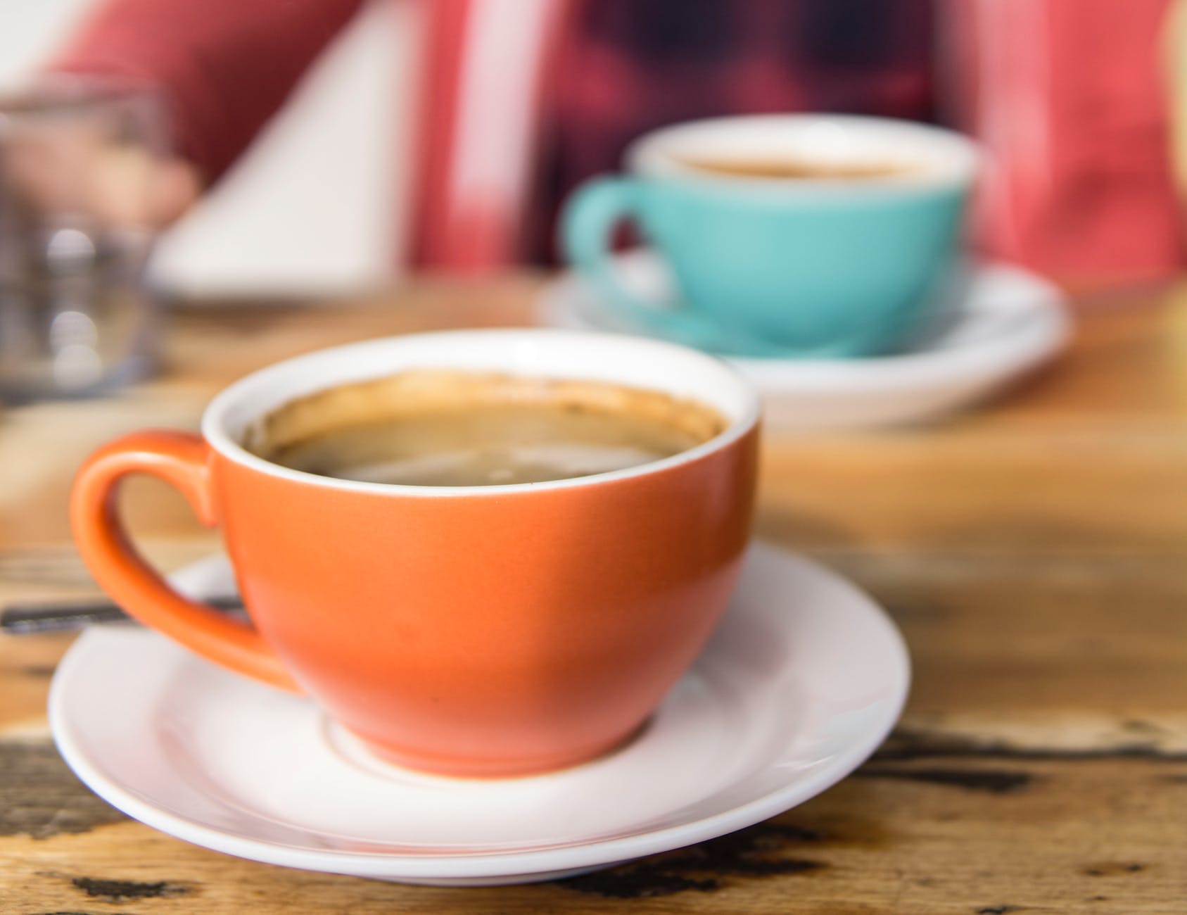 shallow focus photo of orange ceramic mug on white saucer